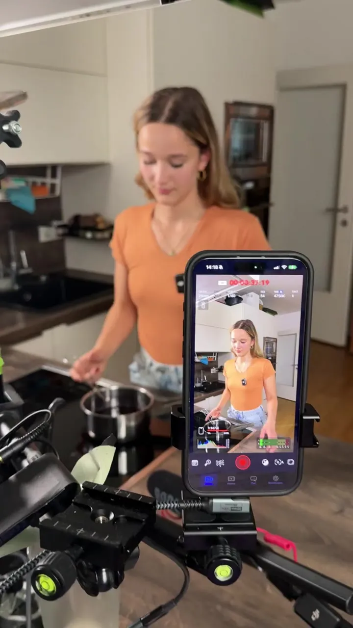 Eine Frau ist am Kochen, im Vordergrund sieht man Video‐Equipment, Halterungen und ein Mikrofon.
